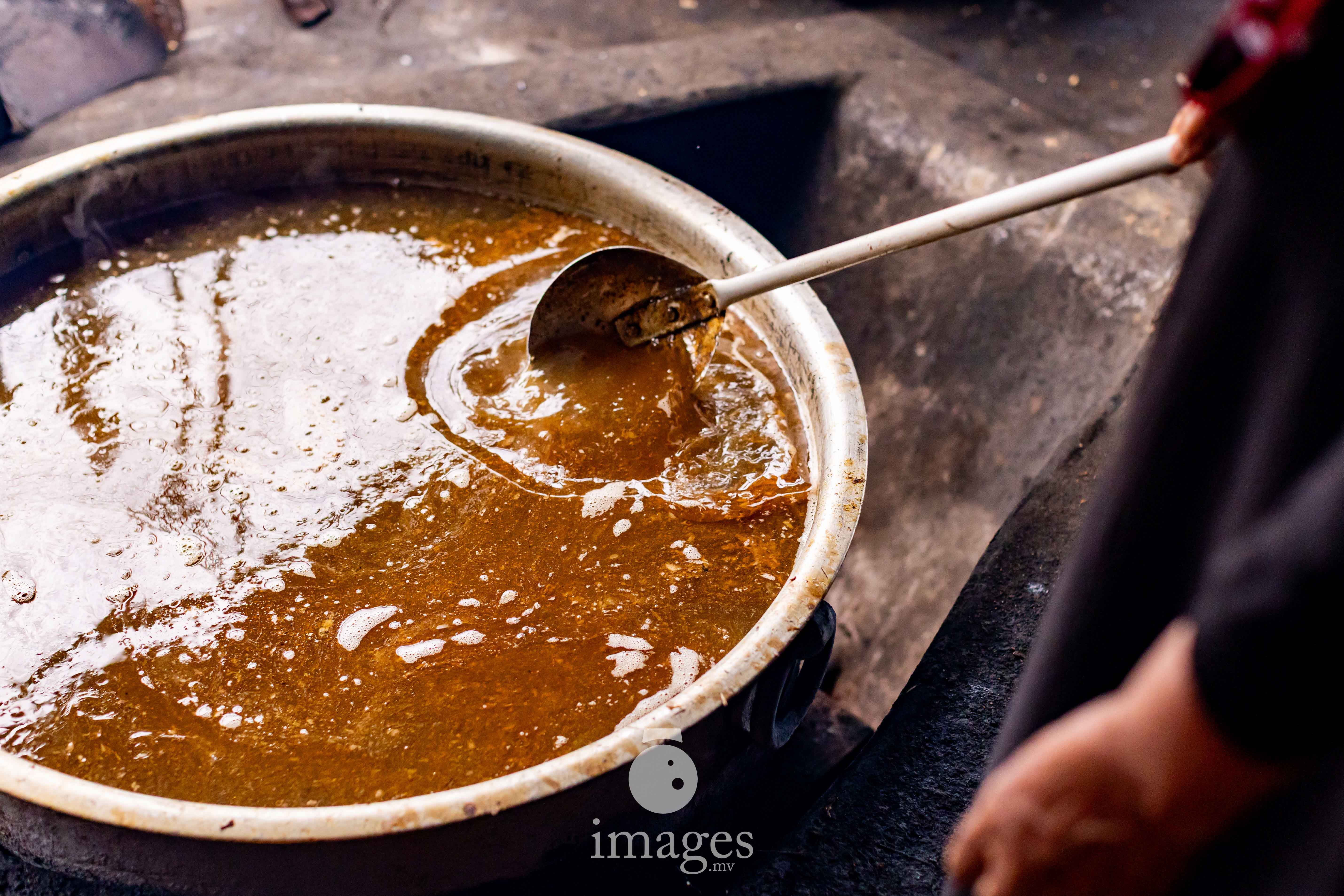 A massive cauldron of tuna stock simmers slowly over open fire, the deep brown liquid gradually reducing into rihaakuru. The slow bubbling marks the first and longest stage of a process perfected over generations.